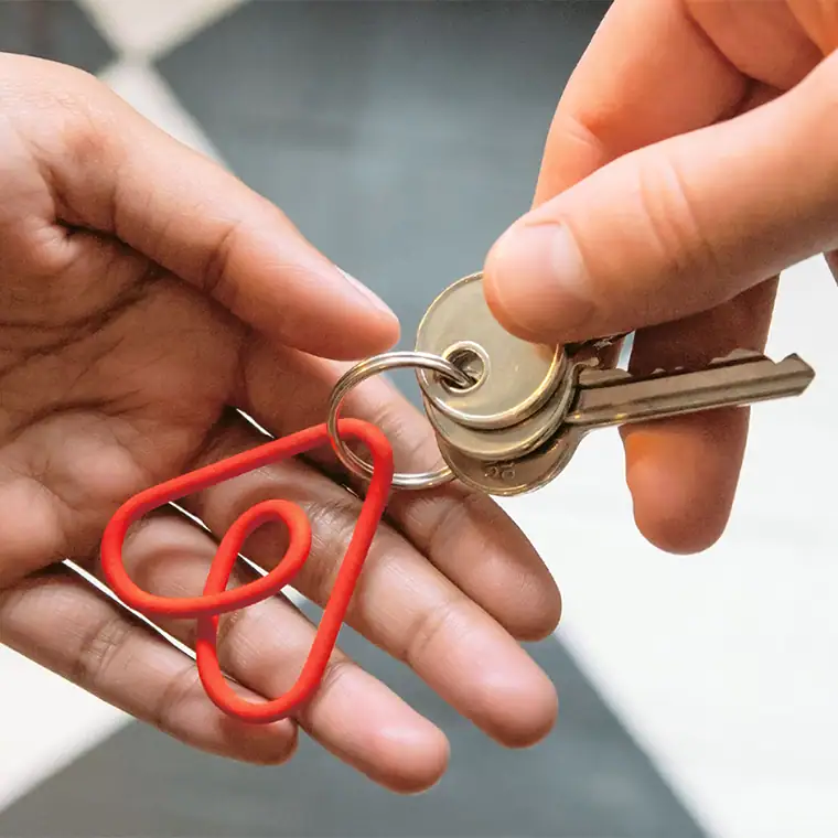 Breloc cu logo-ul Bélo Airbnb — exemplu de identitate vizuală aplicată pe materiale promoționale fizice